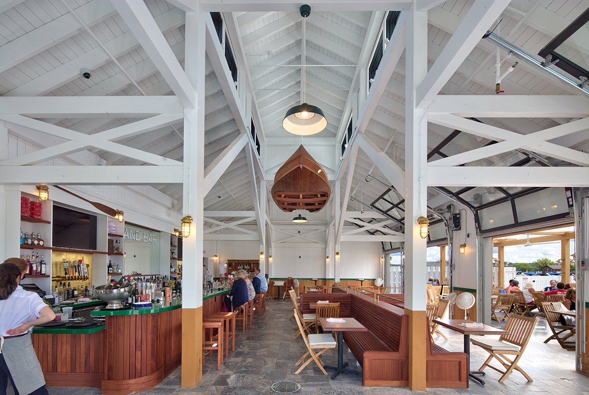The large timber frame interior features a large boat hanging from the rafters.