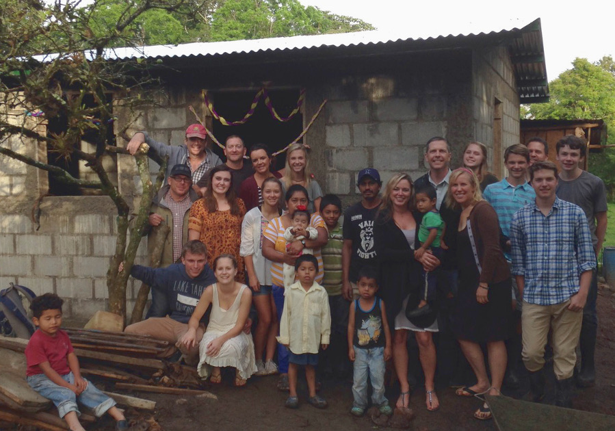 Fifteen volunteers from the Bridges to Community group along with Nicaraguan families gather in front of one of the new homes in El Mojon.