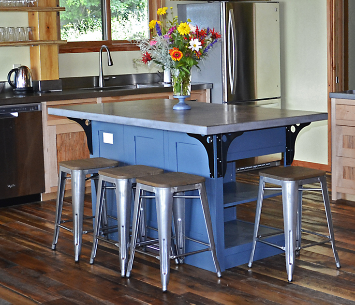 A painted island with a poured top and industrial stools/brackets adds color and functionality to a modest kitchen.