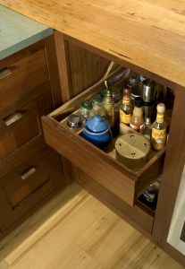 A heavily loaded custom walnut condiment drawer opens weightlessly thanks to TANDEM plus BLUMOTION runner technology.