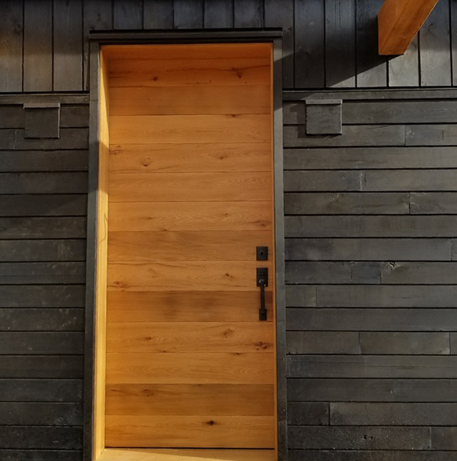 Against traditional shou sugi ban charred siding, a warm-toned reclaimed oak door welcomes all to the Jewel.