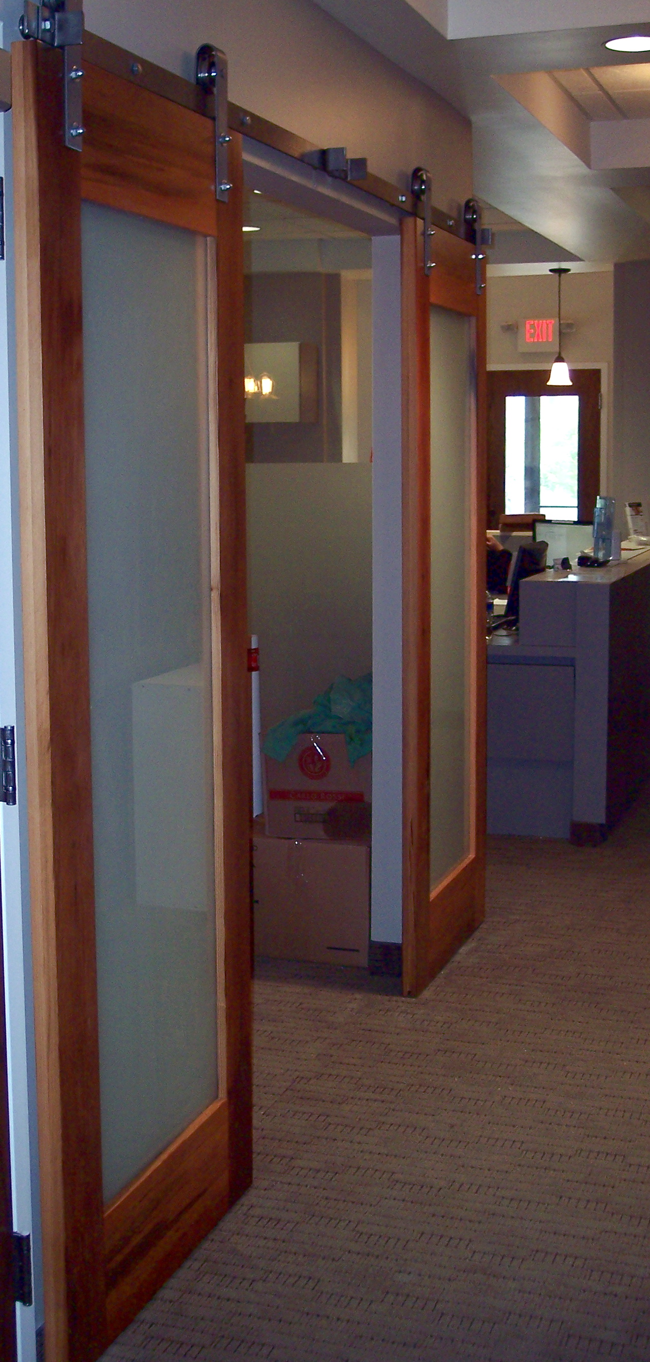 A dental exam room offers easy egress through wood and glass flat track doors.
