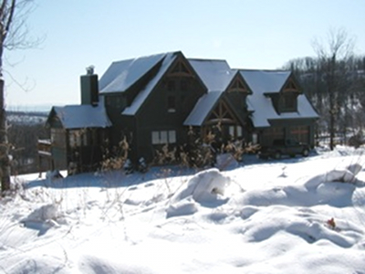 Doug and Ron’s Pennsylvania home sports a traditional green stain with natural exterior Douglas fir trusses. Its sloping site opens to some great views on the back side.