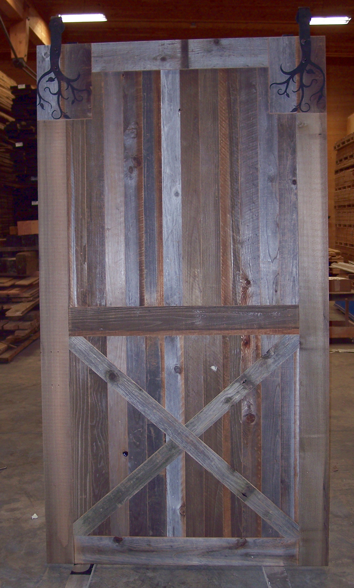 Custom tree “hangers” will support this flat track reclaimed barn wood door.