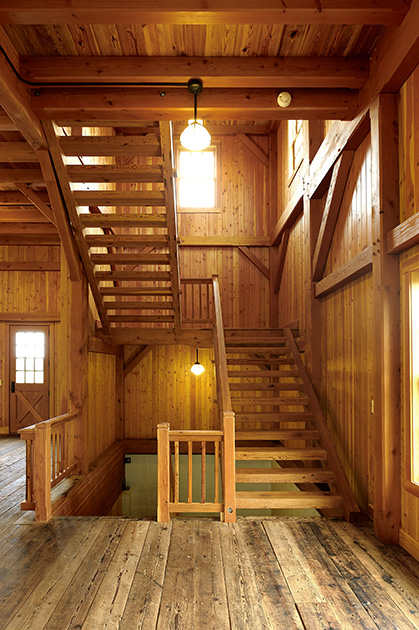 Within a timber frame party barn “floating” stairs connect levels while reminding visitors of open rung ladders common to barn spaces.