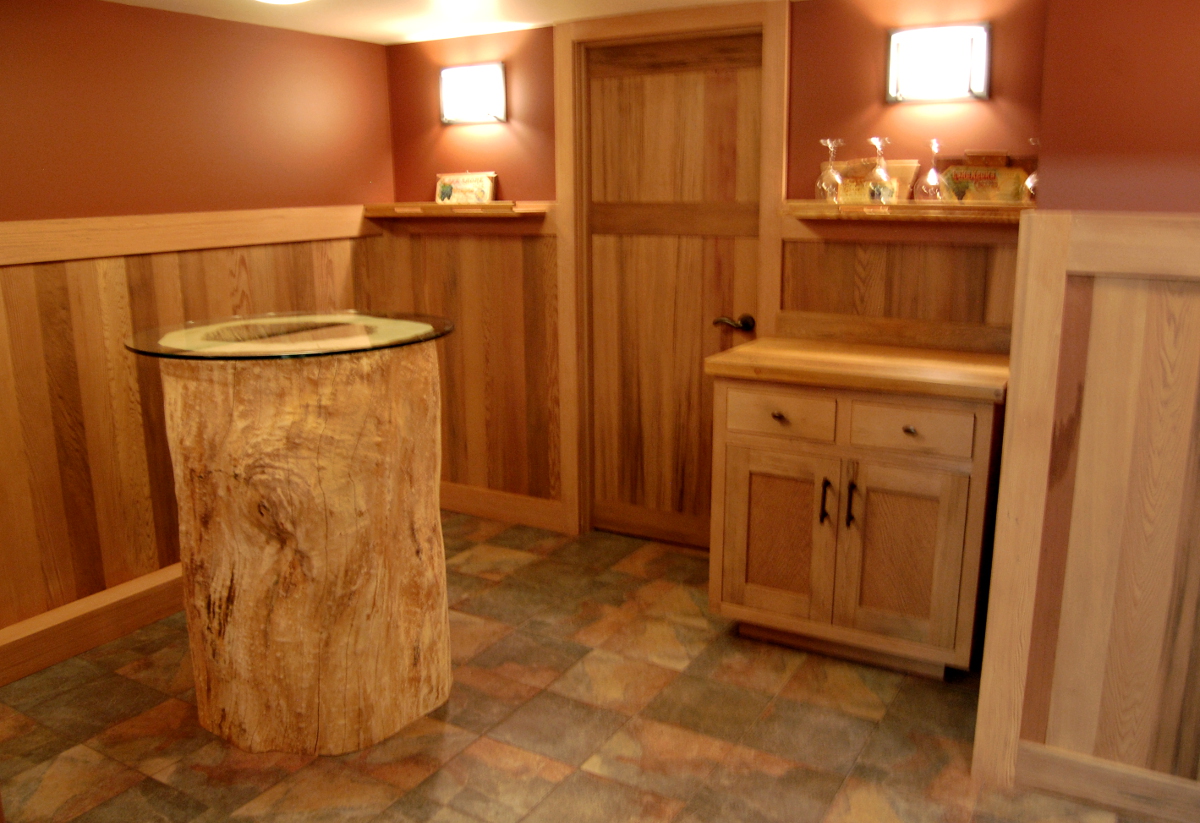 The wine cellar includes a tasting room clad with reclaimed Vat Stock paneling and featuring a maple “trunk” table. The maple tree originally stood on the site and was salvaged during deconstruction of the old home.