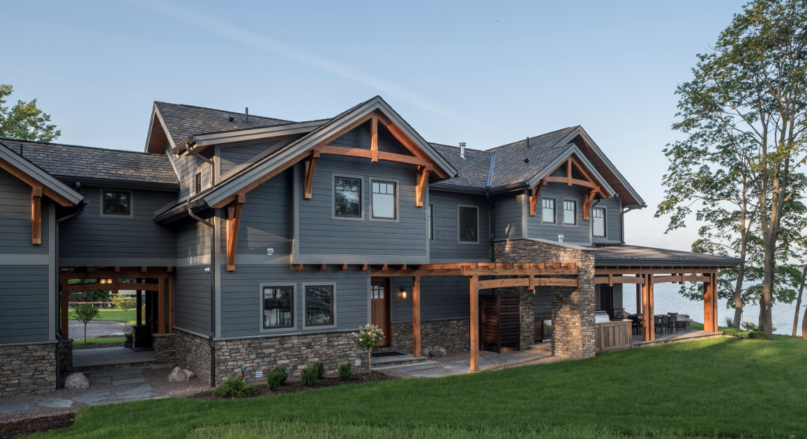 The timber frame breezeway (left) is a favorite feature of the exterior of this project. Sawn curves in the bottom of the paired beams of the breezeway and porch give a consistent craftsman-inspired flow to exterior timber elements.
