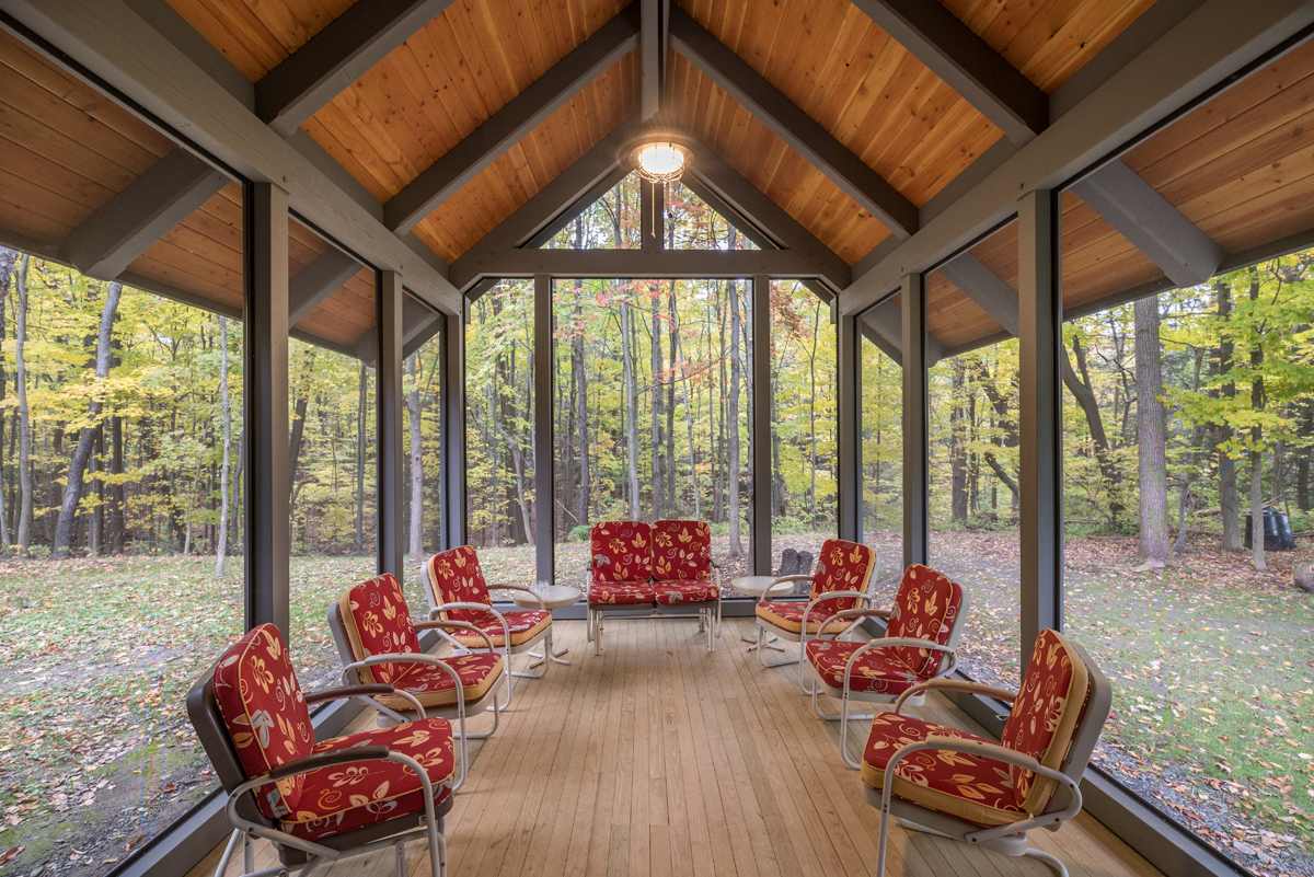 The screen porch extends into the woods, immersed in nature while still providing shelter. Photo (c) Scott Hemenway.