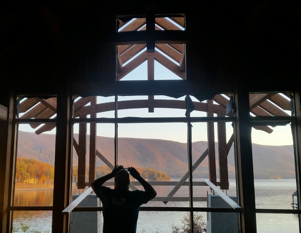 The timber frame helps direct views. Here timber frame craftsman, Jake, paused to capture the lake and late Fall colors through the frame.